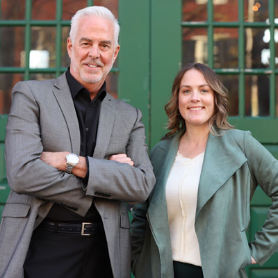 Dean Packer and Cortney Shellenberger smiling beside a brick wall