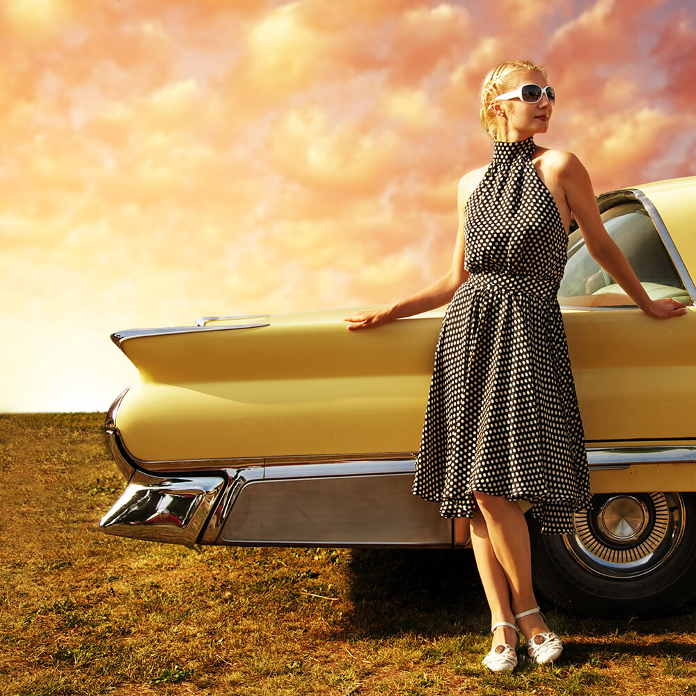 Woman posing beside an antique car