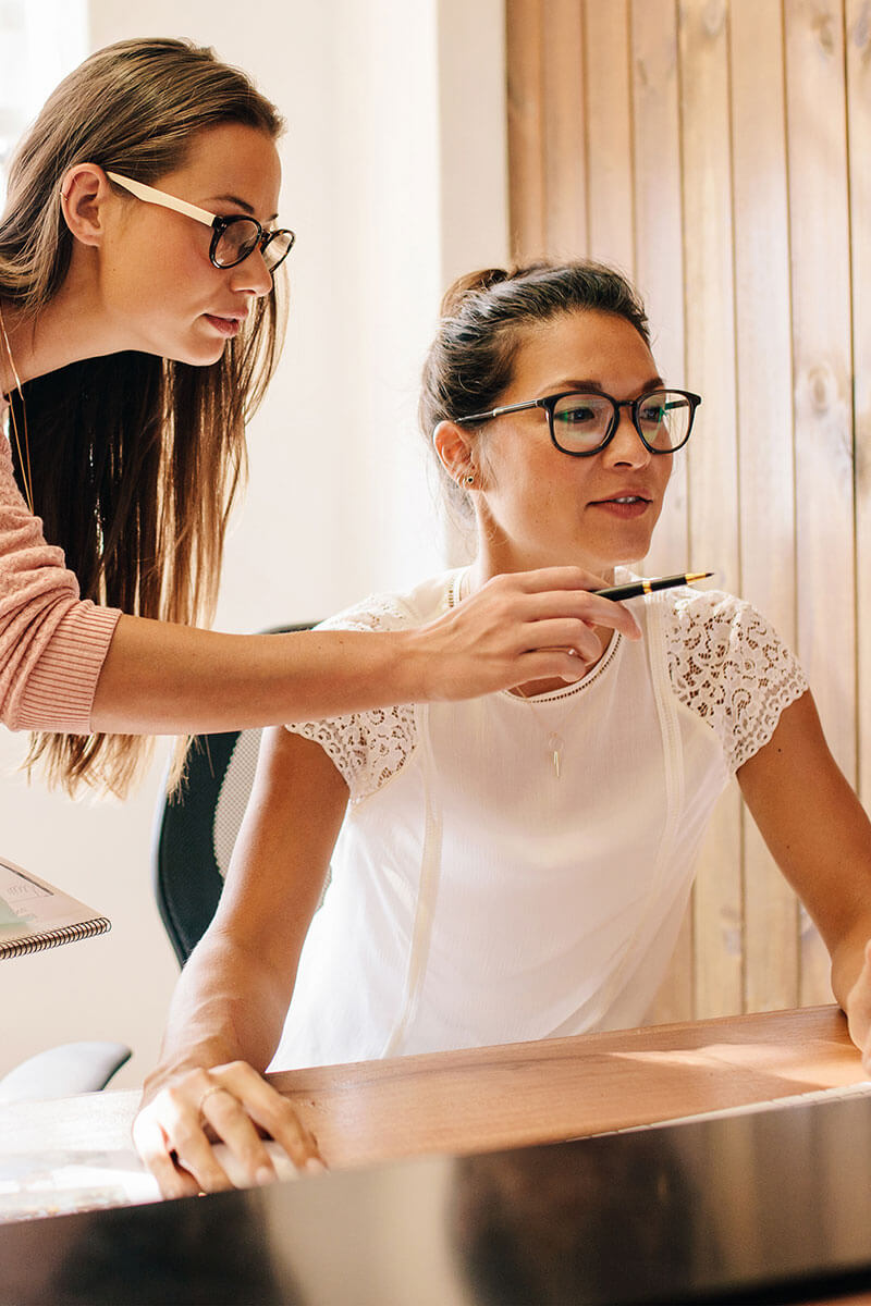 Two women working on a computer and pointing